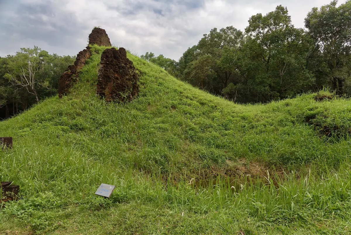 A grassy bomb crater next to temple remains at My Son